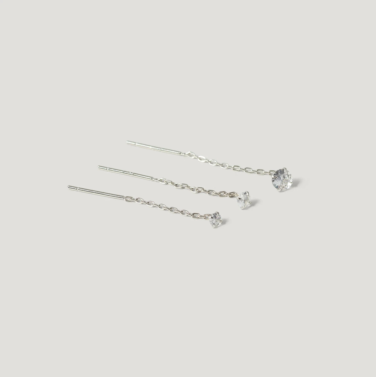 Three silver chain threader earrings with clear gemstone studs, minimalist style