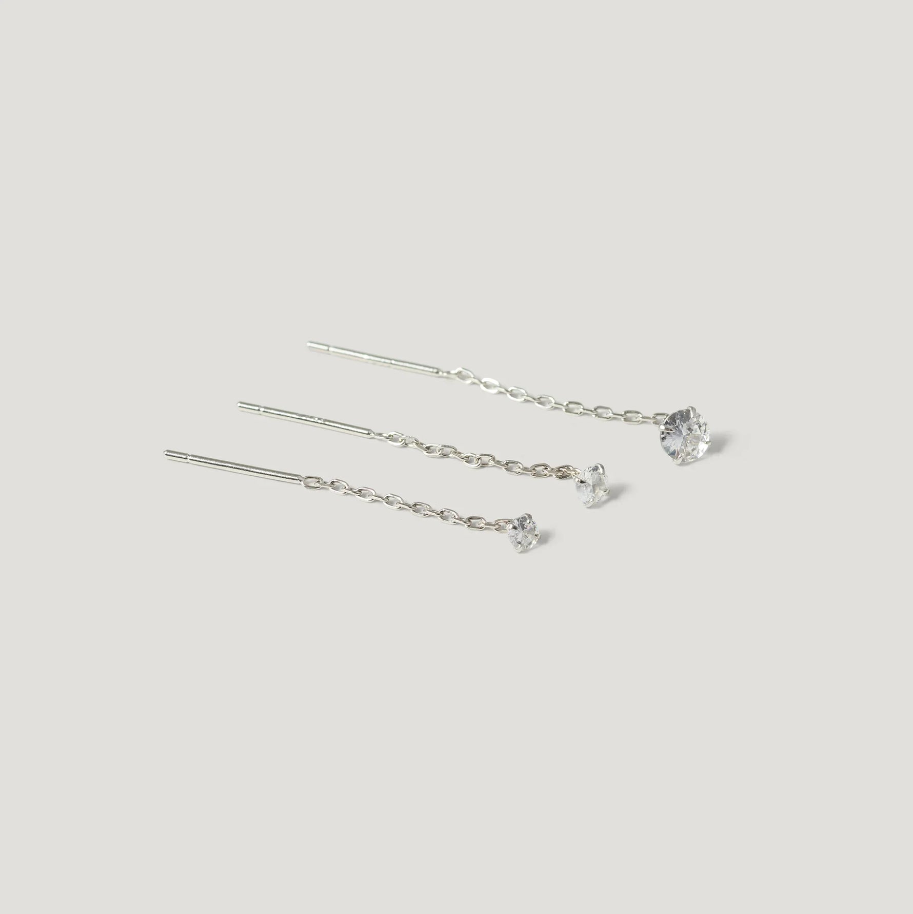 Three silver chain threader earrings with clear gemstone studs, minimalist style
