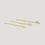 Three gold chain threader earrings with clear gemstone studs on a light background