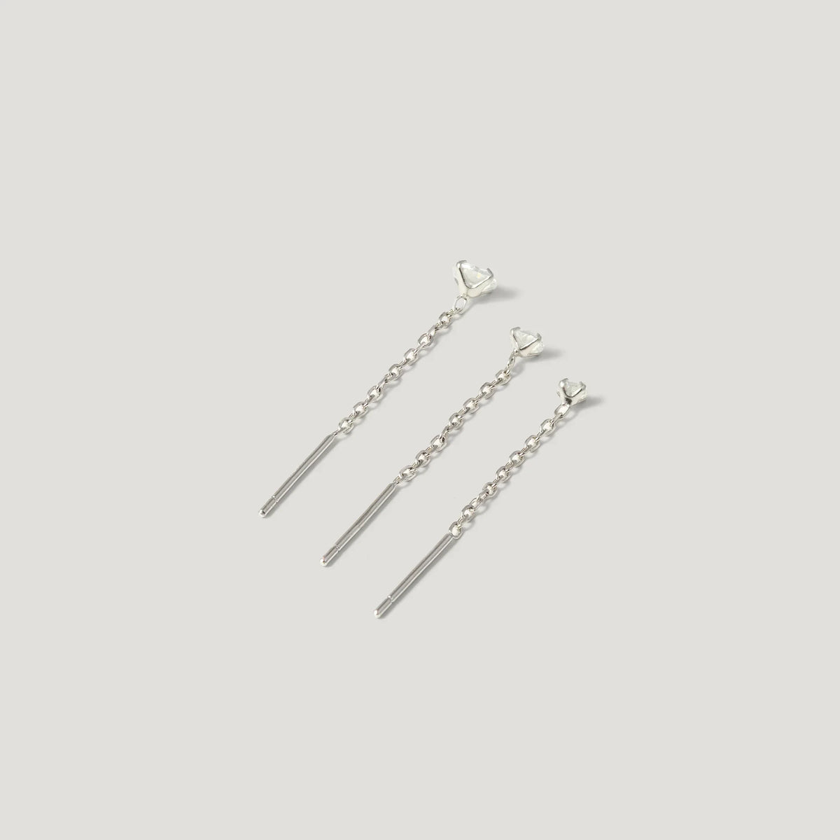 Three silver chain bar earrings with triangle studs on light background