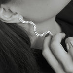 Elegant wavy diamond ear cuff earring on woman's ear, modern jewelry close-up