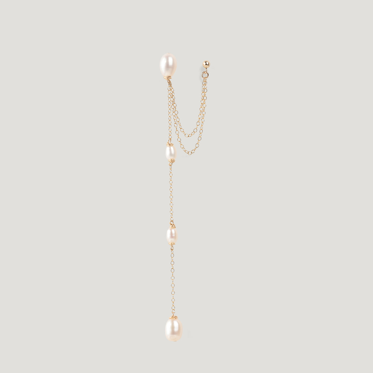 Single gold pearl chain earring with ear cuff, hanging vertically on light background.