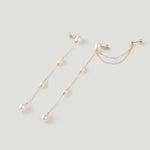 Pair of gold pearl chain earrings at an angle, showing ear cuff and earring backs.