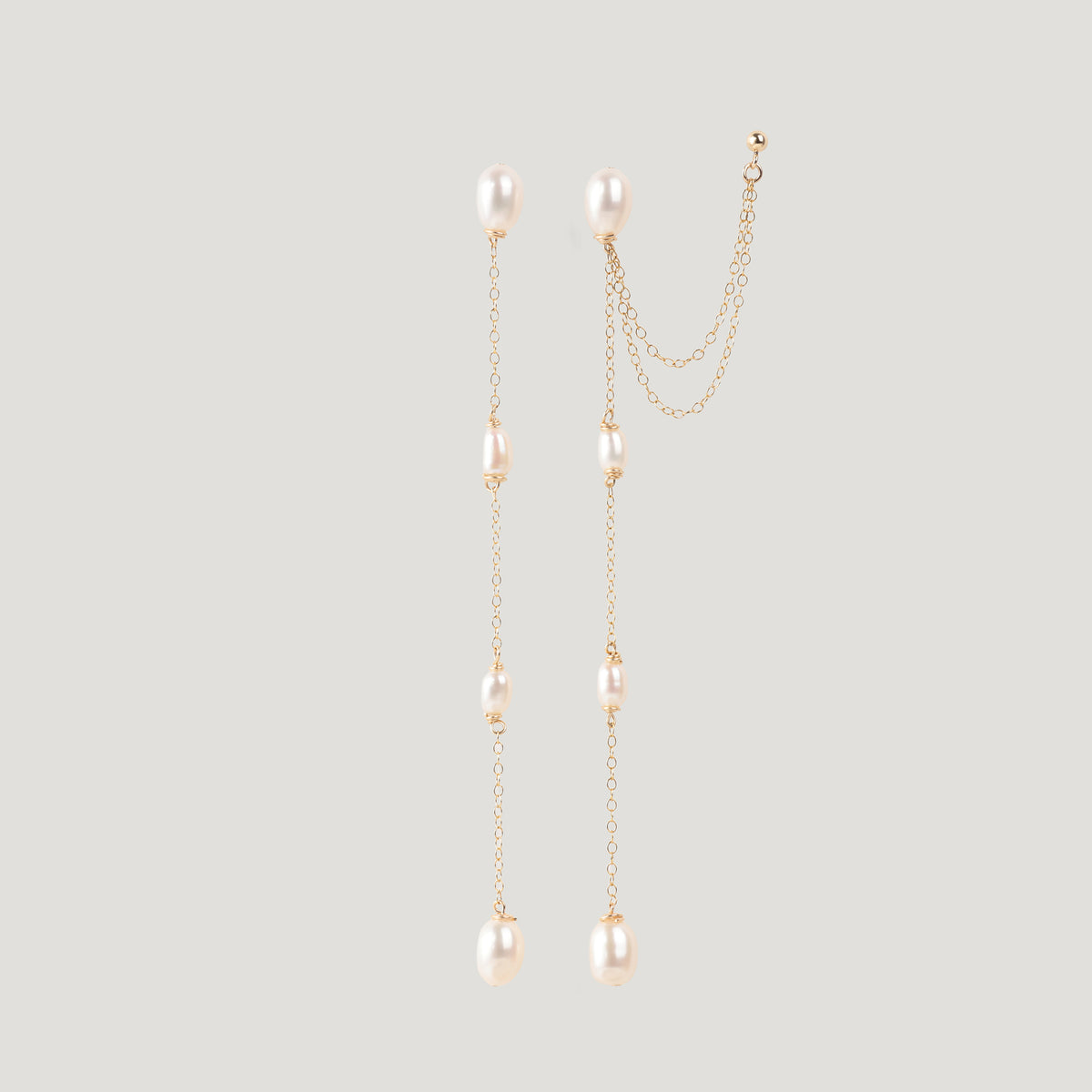 Pair of gold pearl chain earrings hanging straight, one with an ear cuff attached.