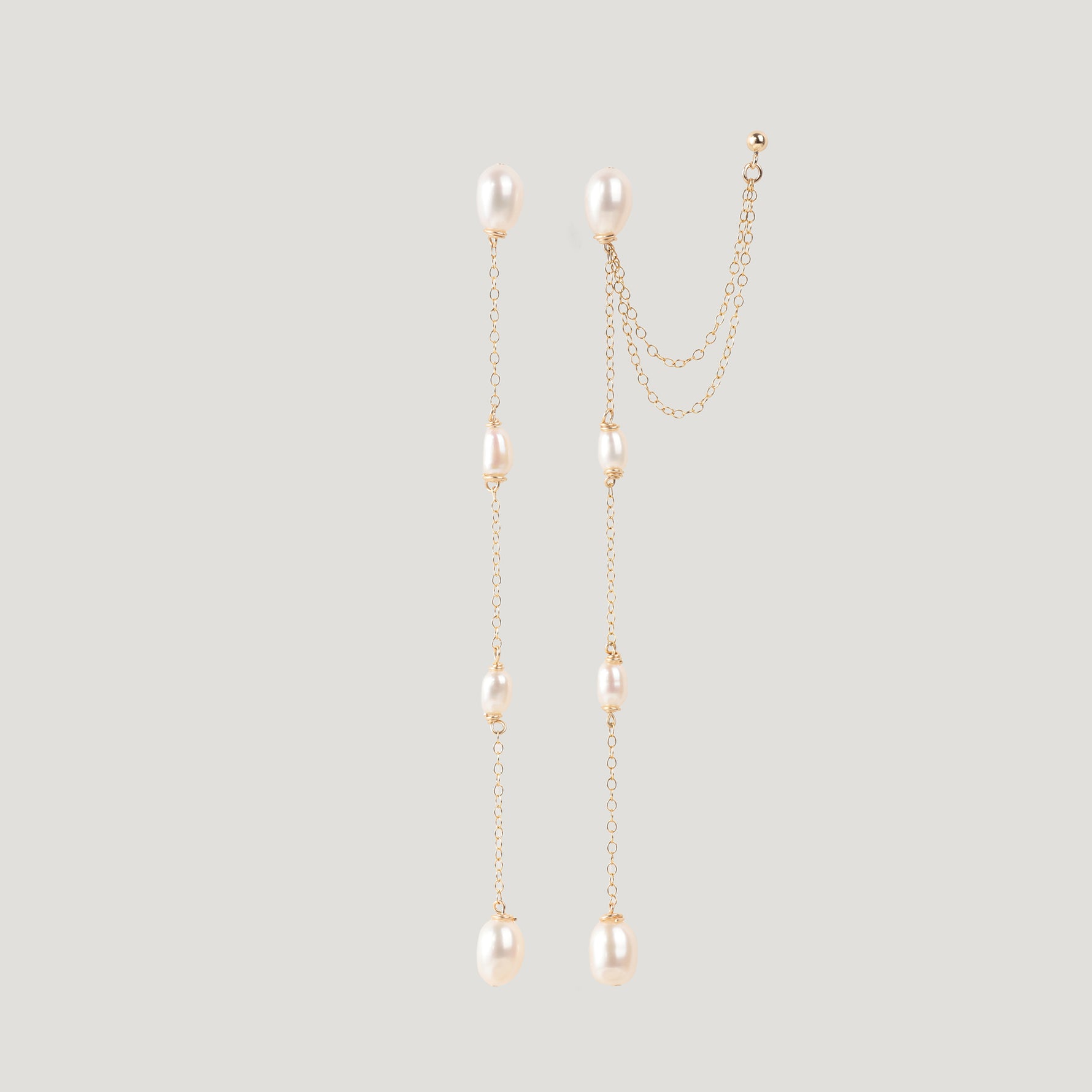 Pair of gold pearl chain earrings hanging straight, one with an ear cuff attached.