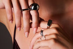 Close-up of woman's hand wearing multiple modern silver rings with geometric designs