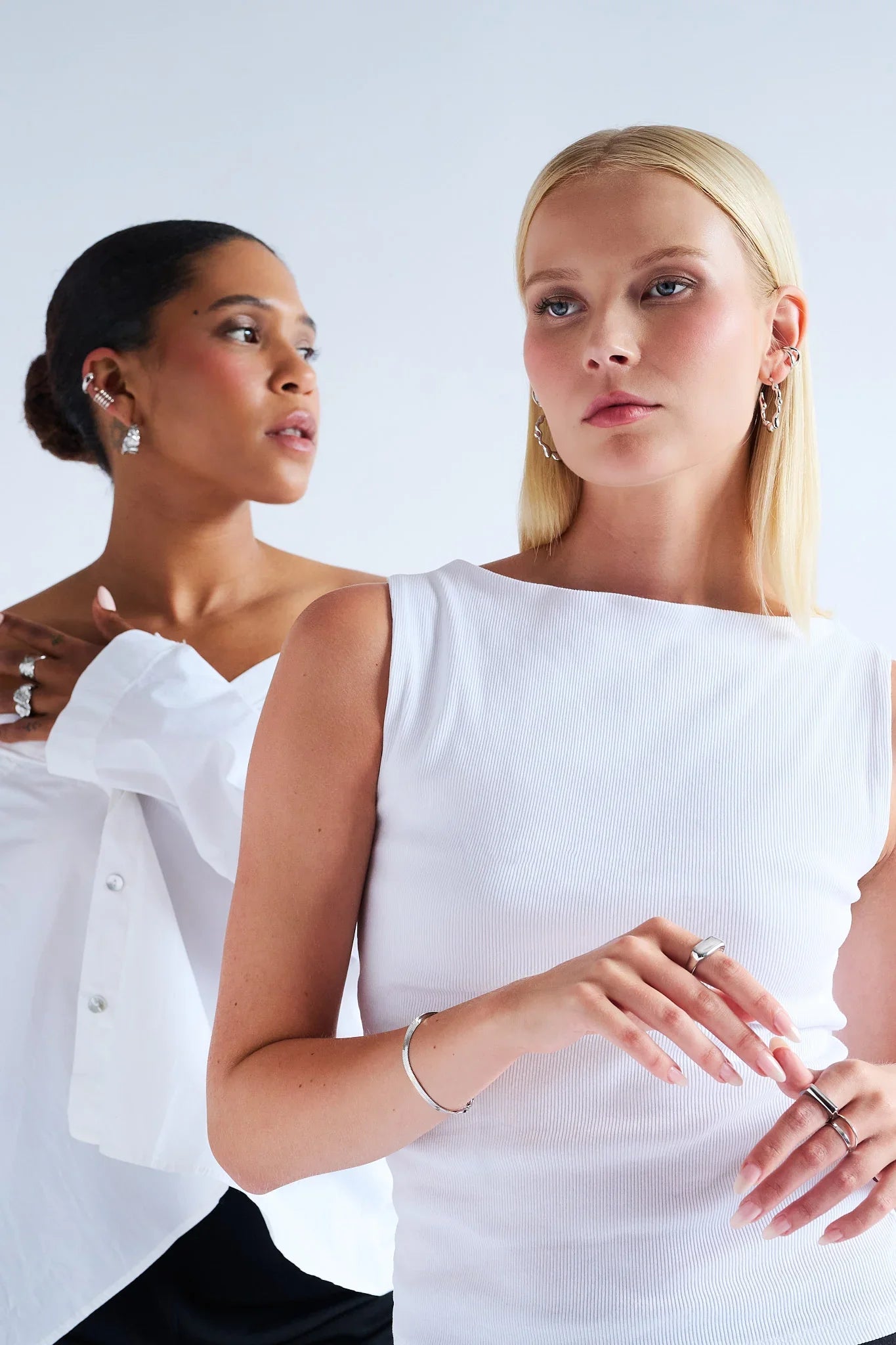 Two women wearing modern silver jewellery, including rings, earrings and bracelet