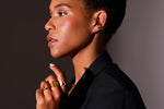 Woman wearing gold statement ear cuff and bold gold letter rings on hand