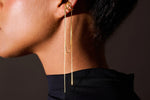 Gold ear cuff earring with long delicate chains on model's ear
