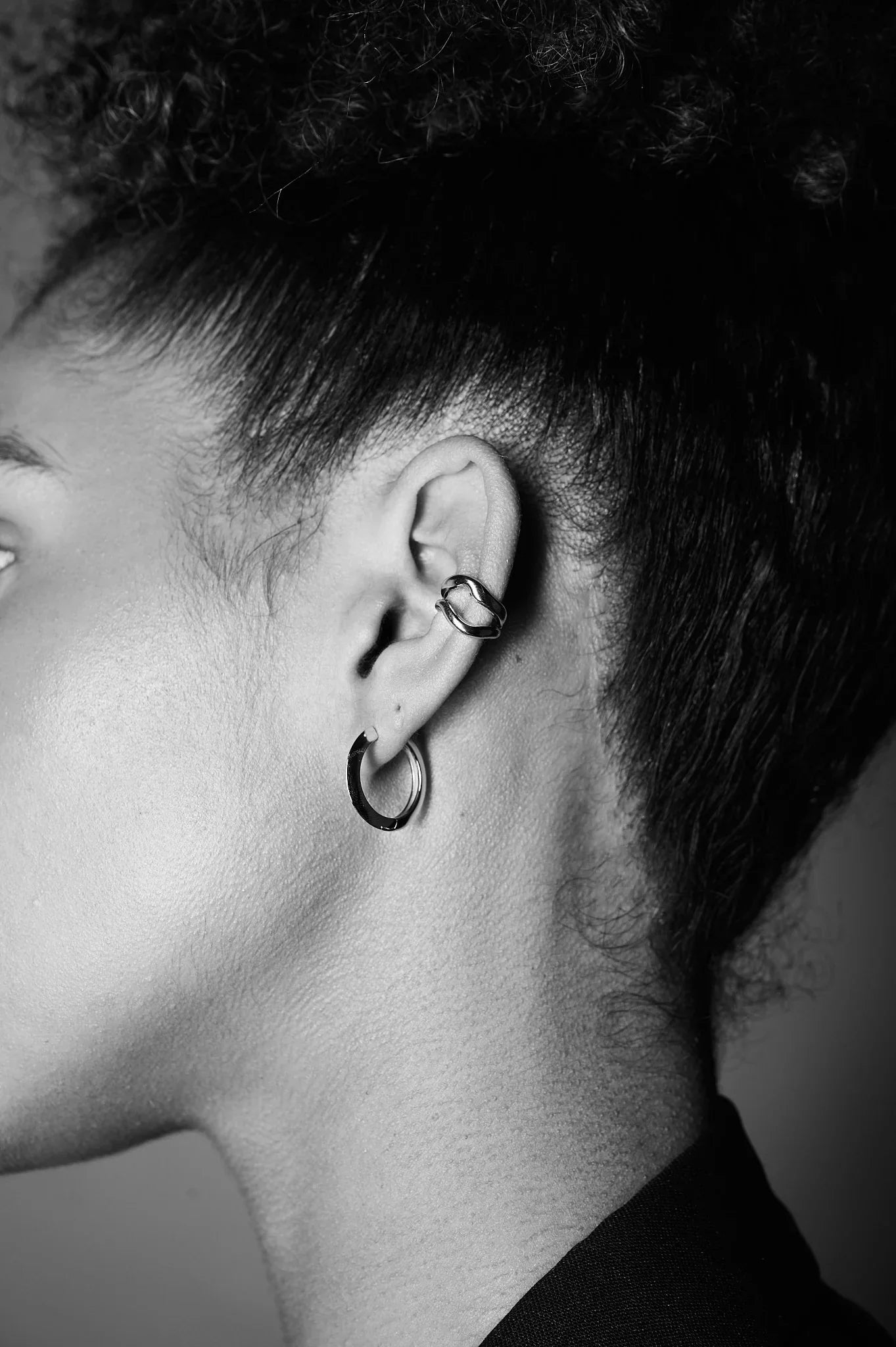 Closeup of a woman's ear wearing two minimalist silver hoop earrings