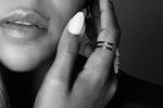 Close-up of a woman's hand with silver stacking rings and chain detail, stylish jewelry