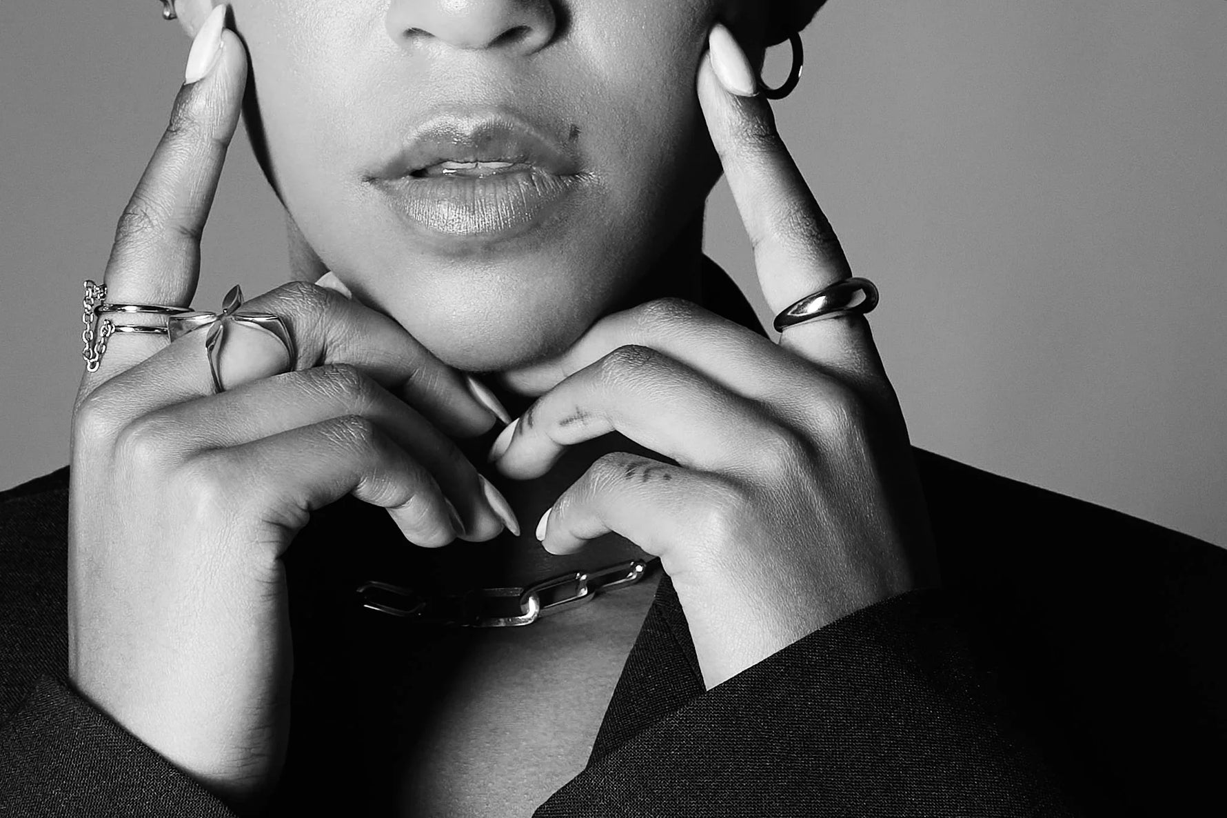 Close-up of woman wearing silver rings and chain necklace, stylish black and white portrait