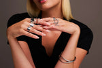 Woman wearing multiple statement silver rings and bangles, showcasing modern jewelry