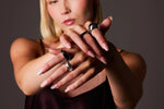 Woman wearing silver statement rings on manicured hands, showcasing contemporary jewellery.