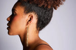 Woman wearing gold hoop earrings with long chain tassels and twisted ear cuff