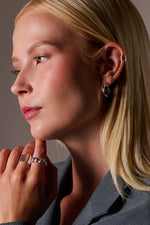 Woman wearing silver earrings and rings, showcasing modern minimalist jewellery