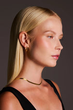 Woman wearing sleek gold hoop earrings and a gold necklace, minimalist jewelry style