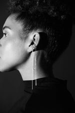 Woman wearing modern long silver chain earring with ear cuff, close-up profile