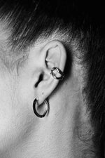 Close-up of an ear wearing a silver ear cuff and a silver hoop earring, minimalist jewelry