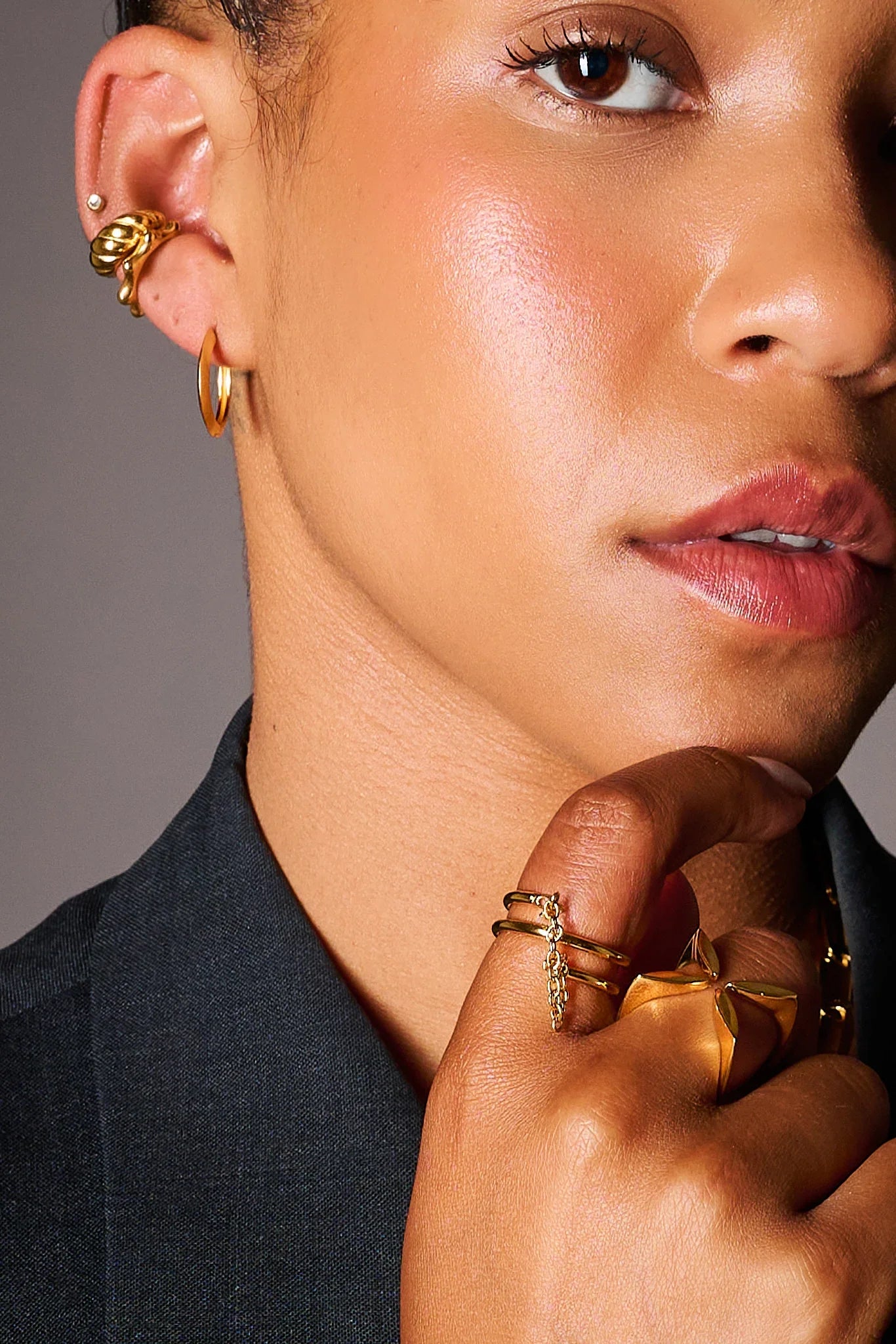 Woman wearing gold earrings and gold rings with unique designs, close-up jewelry shot