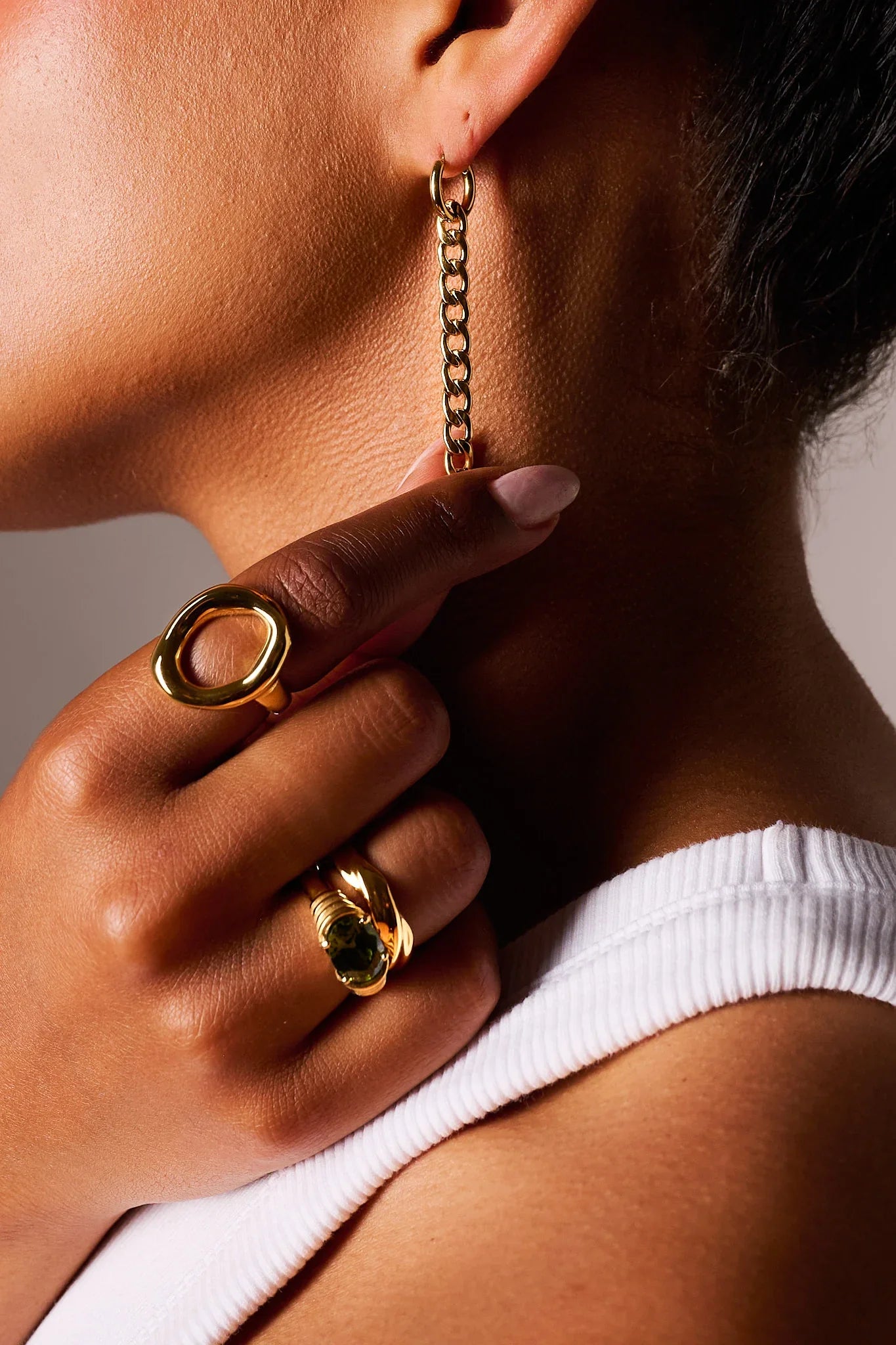 Close-up of person wearing gold chain earring and stylish gold rings