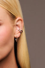Close-up of woman's ear with silver hoop earring and sculpted ear cuff