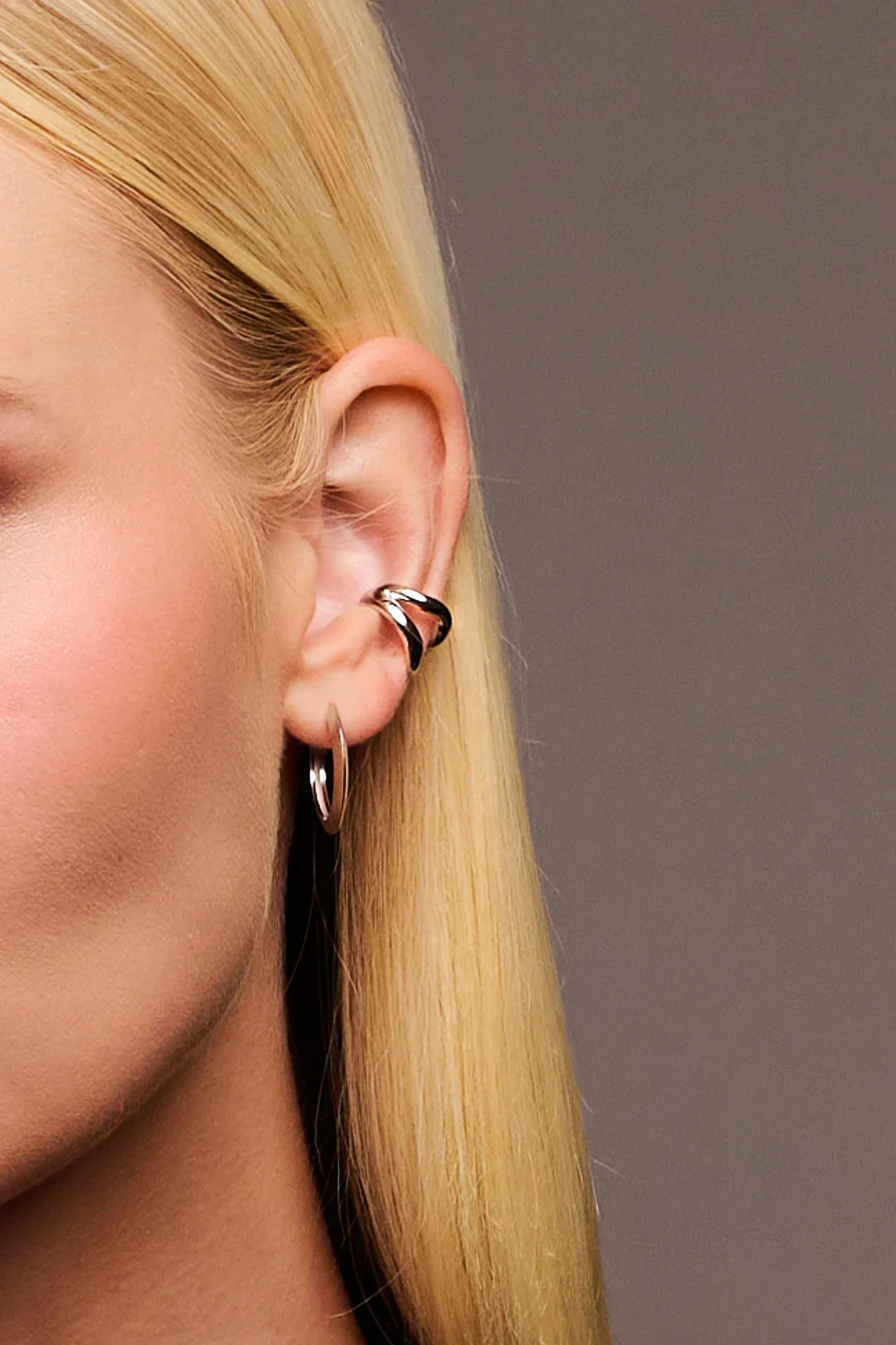 Close-up of woman's ear with silver hoop earring and sculpted ear cuff