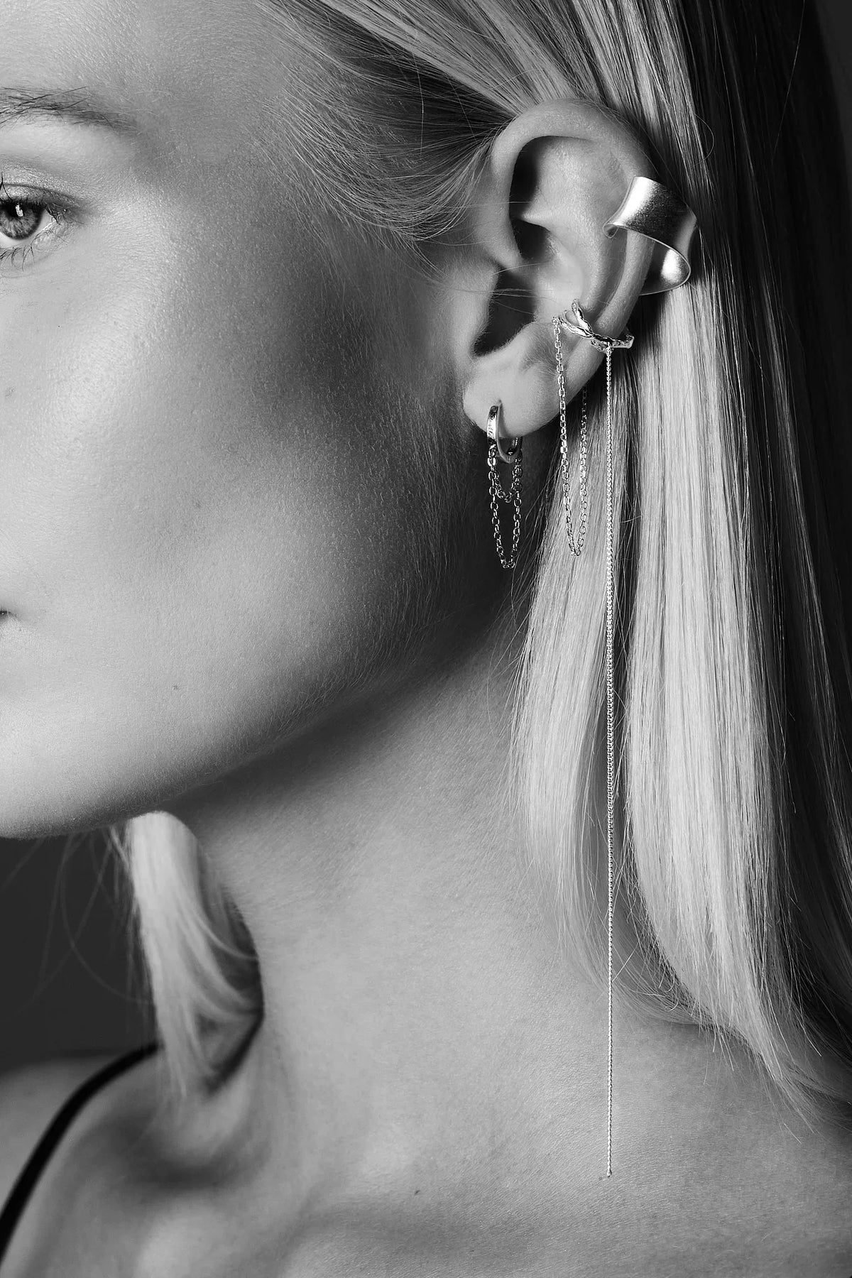Close-up of woman wearing multiple silver ear cuffs and chain earrings