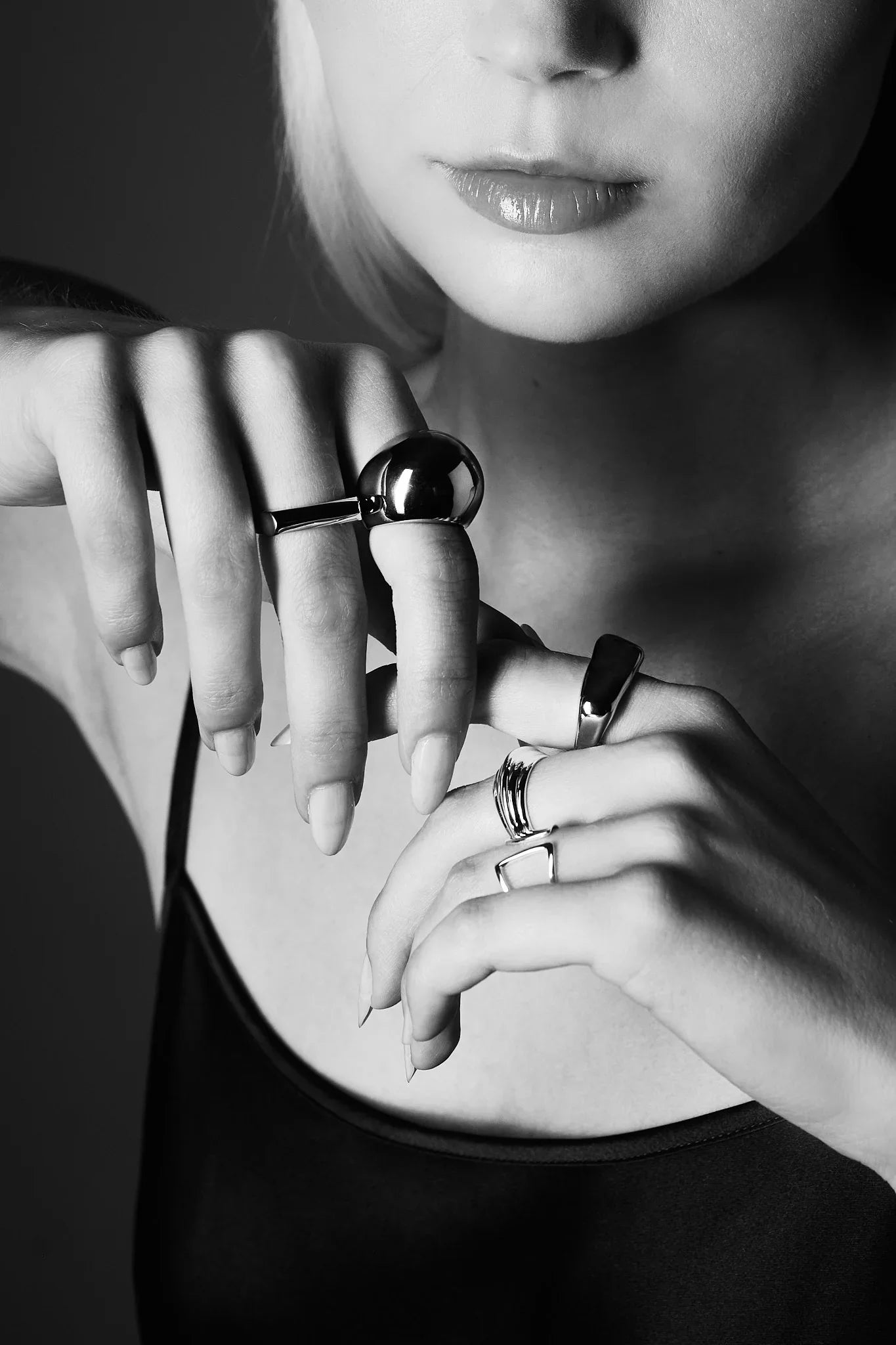 Woman wearing modern silver rings on both hands, close-up black and white photo