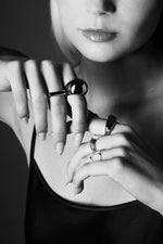 Black and white photo of woman wearing modern silver rings on her fingers