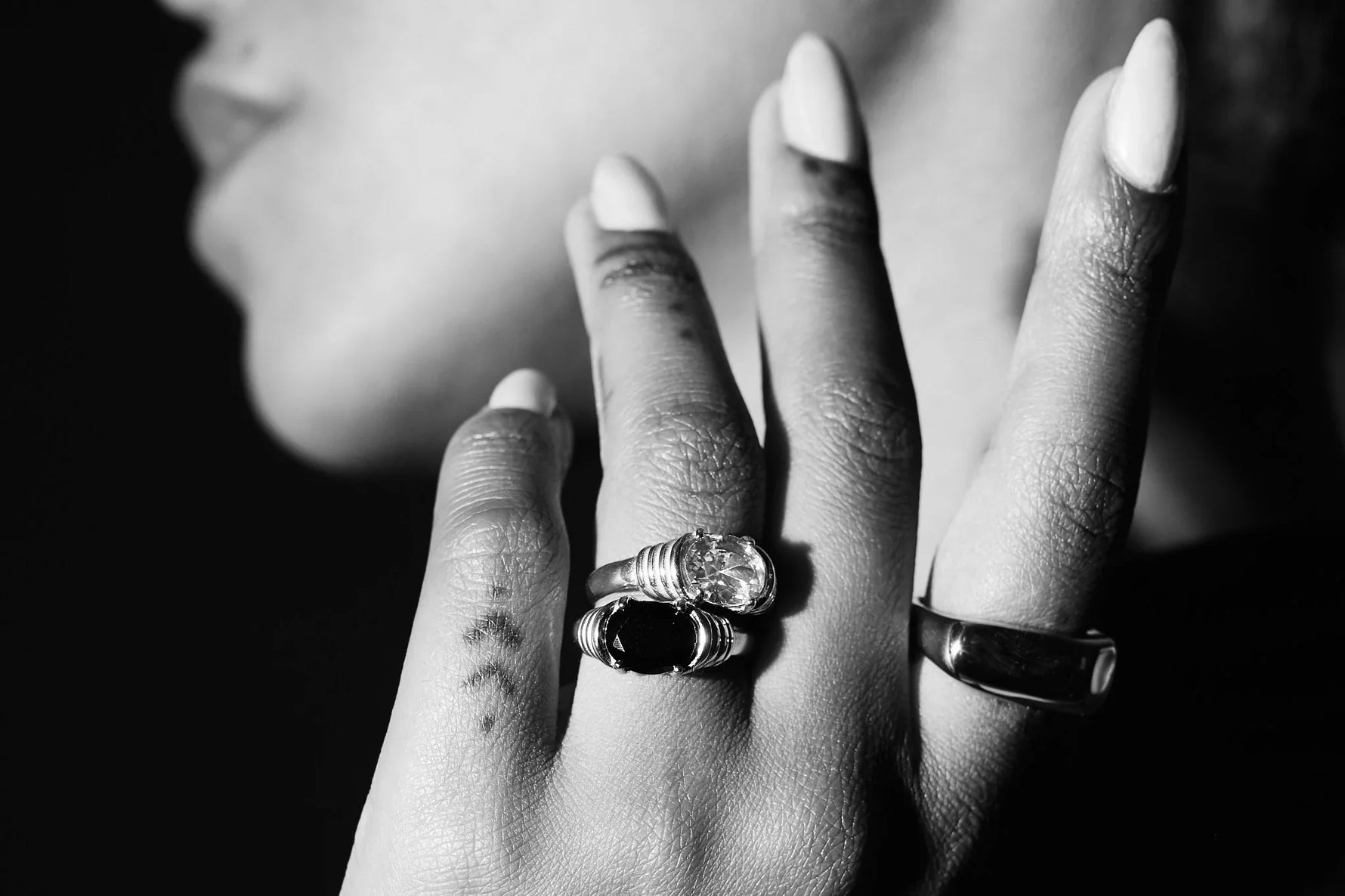 Close-up of hand wearing gemstone rings, elegant silver jewelry, black and white photo