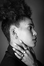 Profile of woman wearing silver rings and hoop earrings, showcasing jewelry details