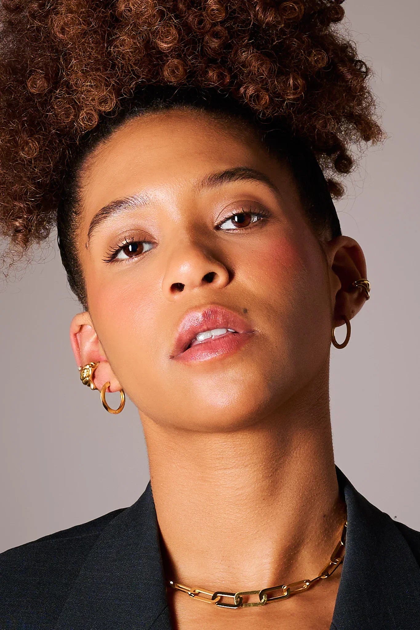 Woman wearing gold hoop earrings and gold chain necklace, close-up jewelry fashion