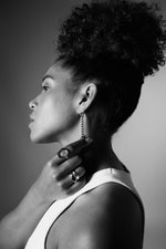 Woman in profile wearing chain drop earring and statement rings, monochrome style