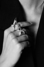 Close-up of a hand wearing two modern silver rings with geometric design, black and white