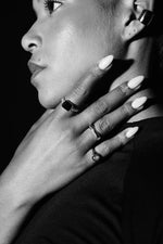 Close-up of woman wearing silver rings, signet ring, and bold ear cuff, showcasing modern jewellery.