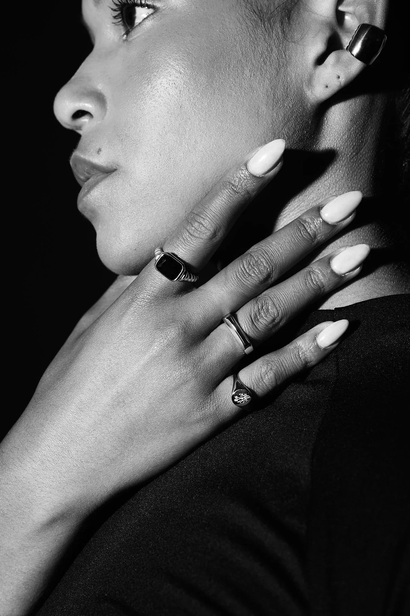 Close-up of woman wearing silver rings, signet ring, and bold ear cuff, showcasing modern jewellery.