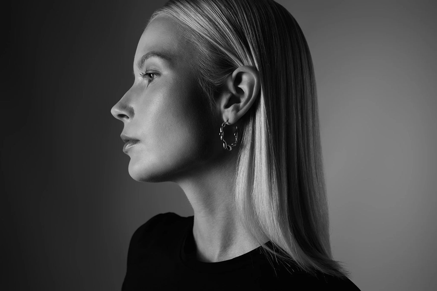 Woman wearing textured hoop earrings, side profile, black and white portrait
