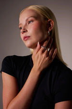 Woman wearing silver rings and hoop earring, hand near face, minimal jewelry style