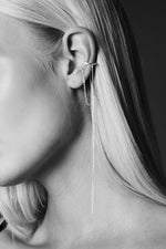 Close-up of a woman's ear wearing a modern silver ear cuff with delicate chain detail