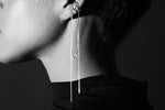Minimalist silver ear cuff and long chain earring on model in black and white