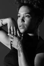 Black and white portrait of woman wearing multiple silver rings, bracelets, and earrings