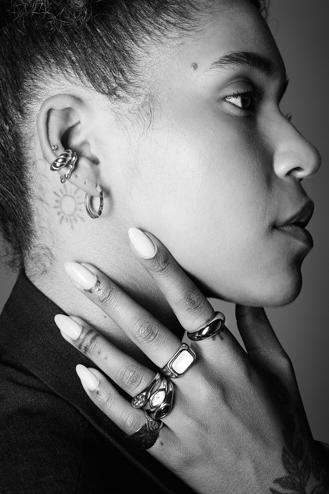 Close-up of woman wearing silver rings and hoop earrings, showcasing modern jewellery