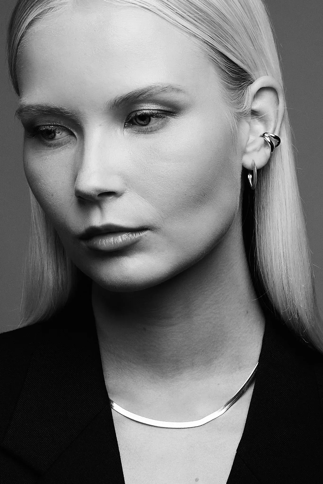 Woman wearing minimalist silver necklace and modern hoop and ear cuff earrings