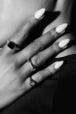 Close-up of hand with long nails wearing three elegant silver rings in black and white
