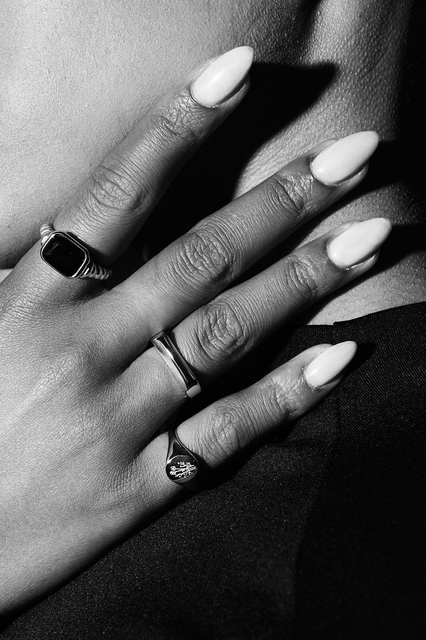 Close-up of hand with long nails wearing three elegant silver rings in black and white