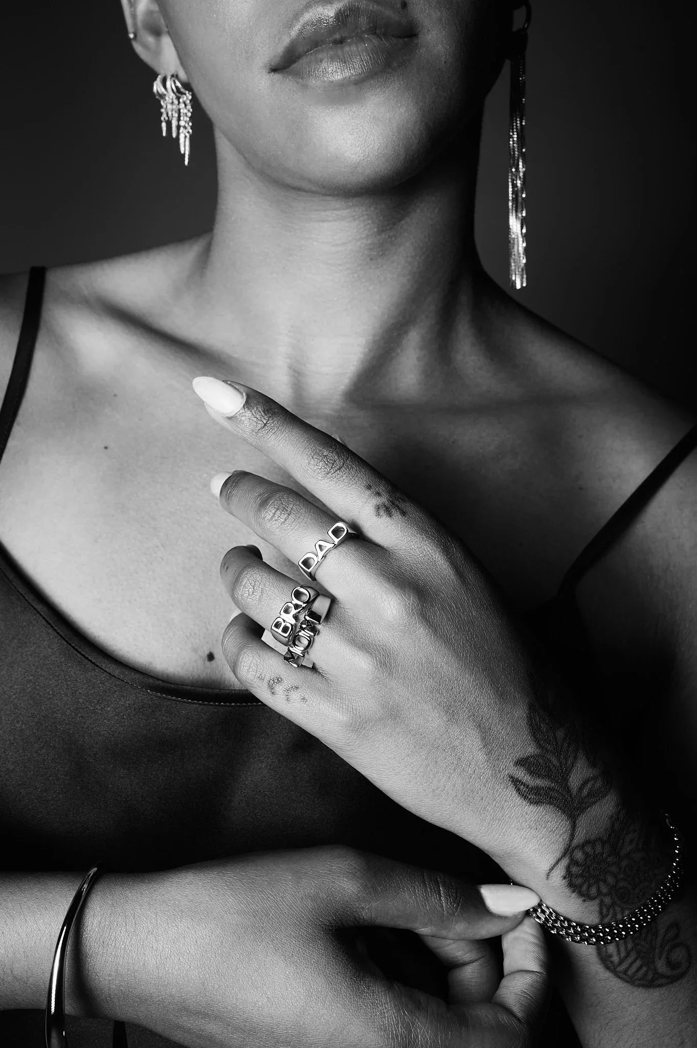 Close-up of woman wearing silver statement rings, earrings, and bracelet, showcasing jewelry details.