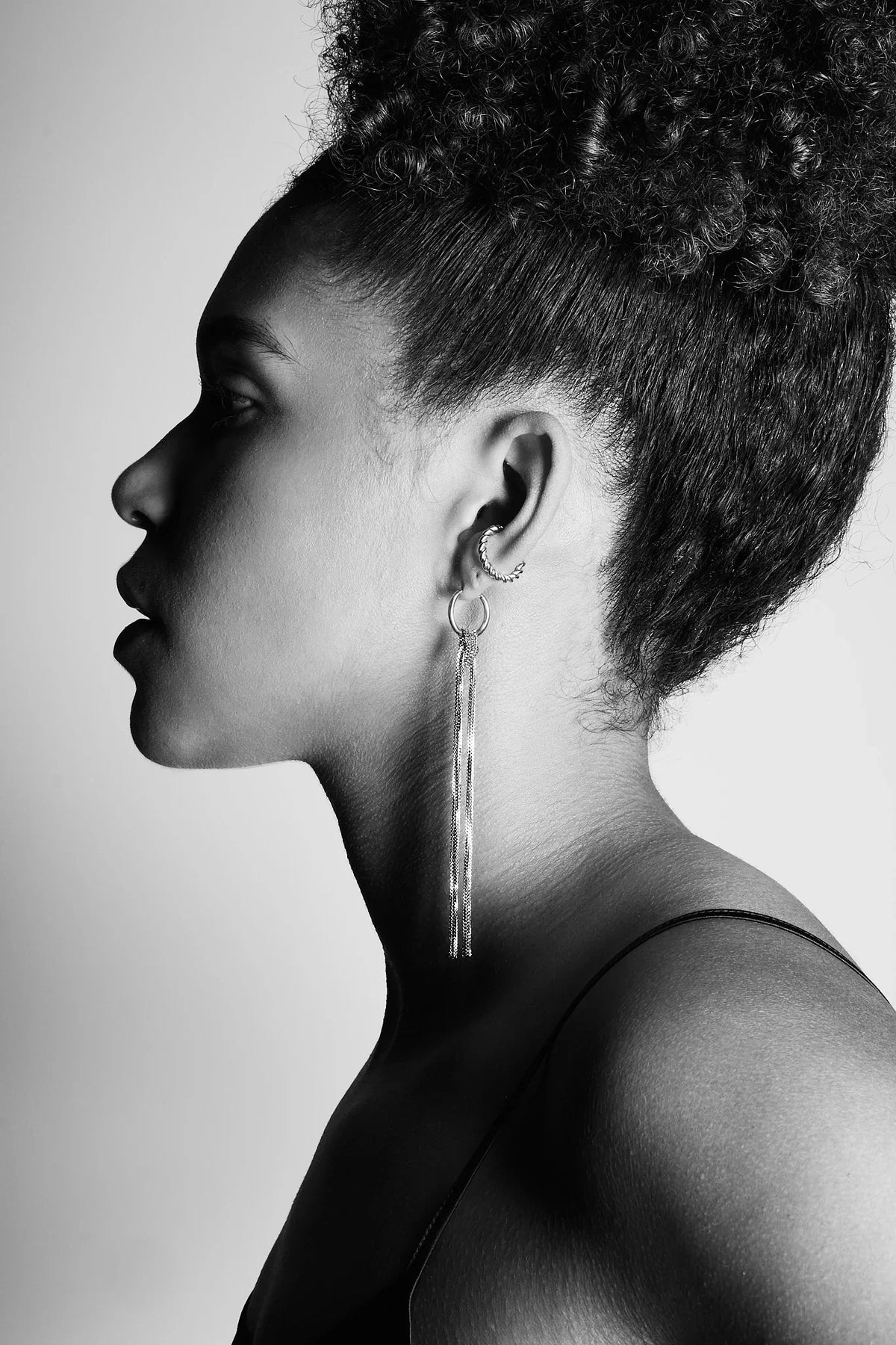 Woman in profile wearing long chain drop earrings and ear cuff, black and white