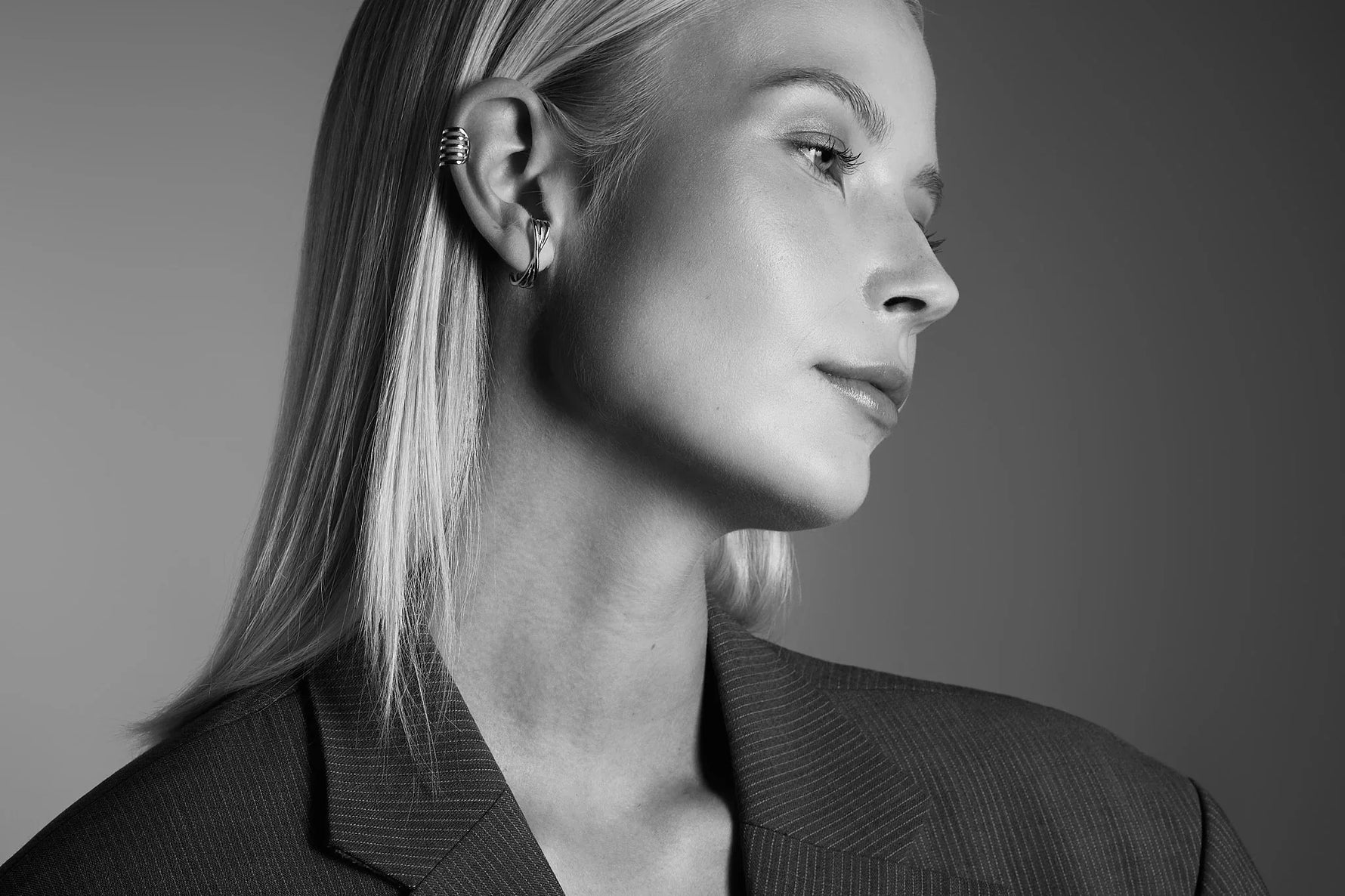 Woman wearing modern silver hoop earrings and ear cuff, minimalist style