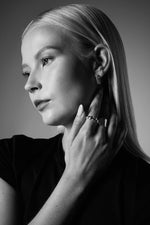 Woman wearing silver hoop earrings and twisted silver rings, elegant jewellery close-up
